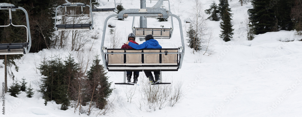 Naklejka premium Two skiers on chair-lift in gray day