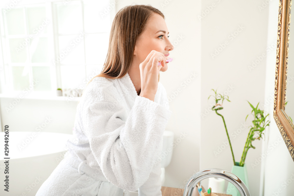 Woman brushing teeth in bathroom