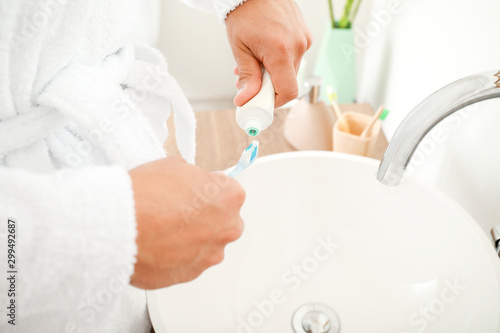 Young man brushing teeth in bathroom, closeup © Pixel-Shot