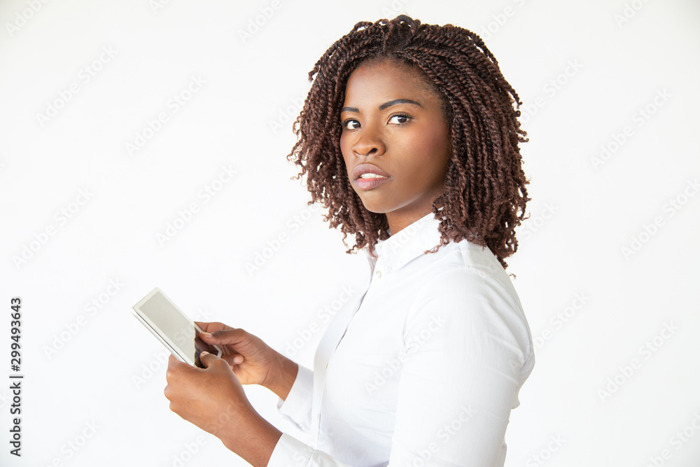 Serious excited professional watching content on tablet, looking at camera. Young African American business woman standing isolated over white background. Internet communication concept Serious excited professional watching content on tablet, looking at camera. Young African American business woman standing isolated over white background. Internet communication concept