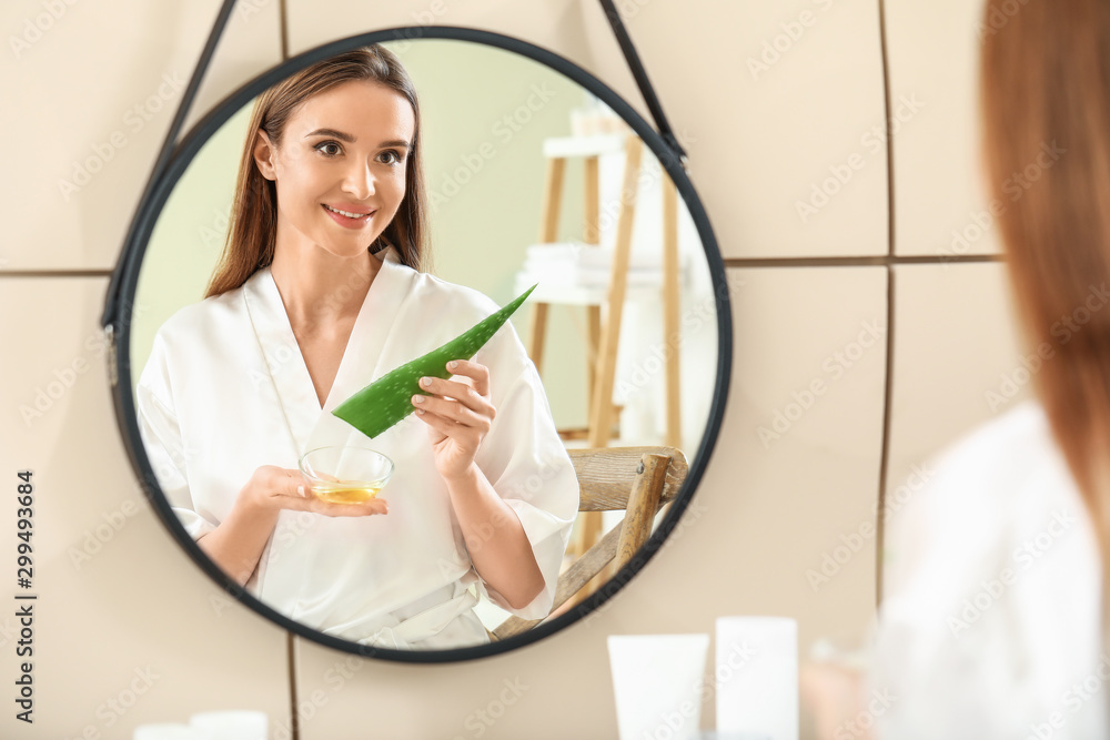 Beautiful young woman using aloe vera in bathroom