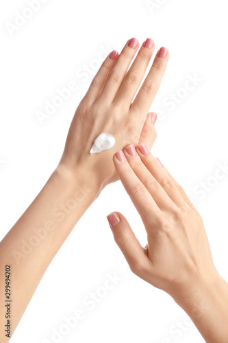 Young woman applying hand cream against white background