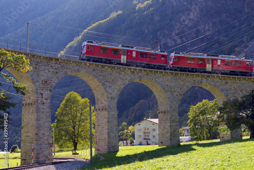 Swiss mountain train Bernina Express passes the spiral of the Brusio Viaduct