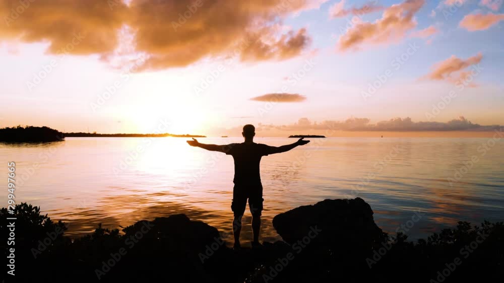 Man with outstretched arms in front of sunset Man with outstretched arms in front of sunset