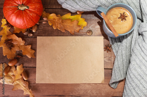 Grey cup of coffee with milk and spices, scarf, yellow oak leaves, acorns, orange pumpkins on dark brown wooden table. Welcome Autumn concept. Fall, spicy latte, thanksgiving, top, copy space