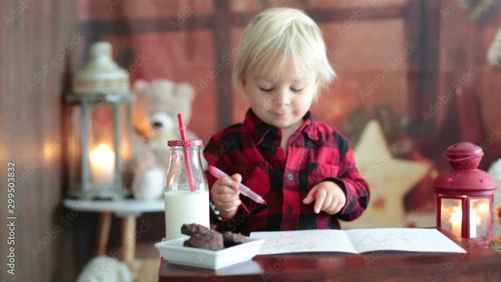 Sweet blonde toddler boy, writing letter to Santa, wishing presents for the holidays Sweet blonde toddler boy, writing letter to Santa, wishing presents for the holidays
