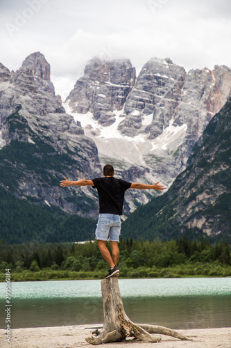 Man standing and loo on the Big majestic mountains, view of Lake Landro Lago di Landro Cristallo group the Dolomites, Italy