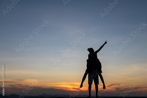 Silhouette couple in love on the tropical beach on background colorful sunset