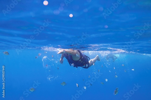Man in the life-jacket swiming in the blue sea water