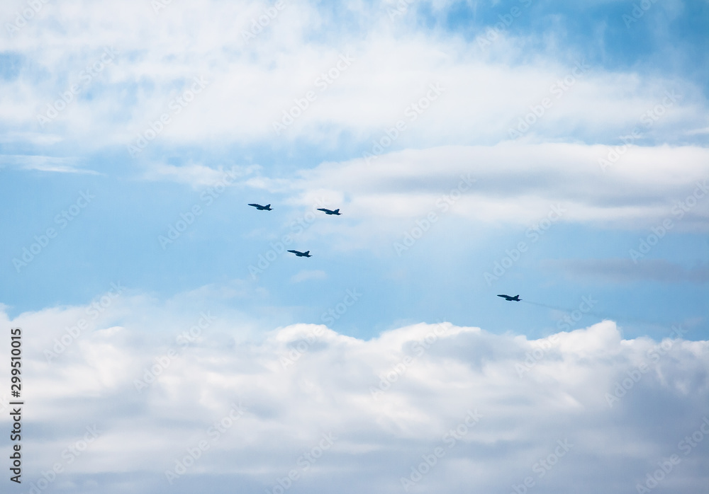Four fighter planes flying in formation in some maneuvers on October 12, is Spain with a cloudy blue sky background