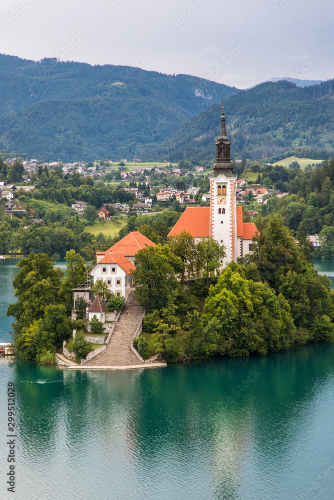Bled, Slovenia - July, 2019: Lake Bled with St. Marys Church of Assumption on small island. Mountains and valley on background. Space for your text.