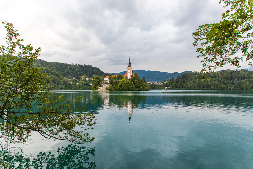 Obraz premium Bled, Slovenia - July, 2019: Lake Bled with St. Marys Church of Assumption on small island. Mountains and valley on background. Space for your text.