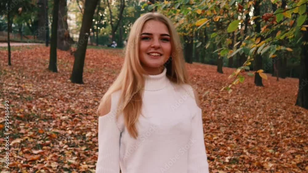 Autumn girl portraits. Model in white sweater Yellow leaves. Atmospheric video
