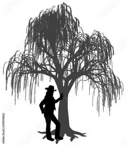Young woman with hat is leaning against a weeping willow tree. Woman leaned a hand on trunk of weeping willow tree. Young girl is standing under a weeping willow tree.