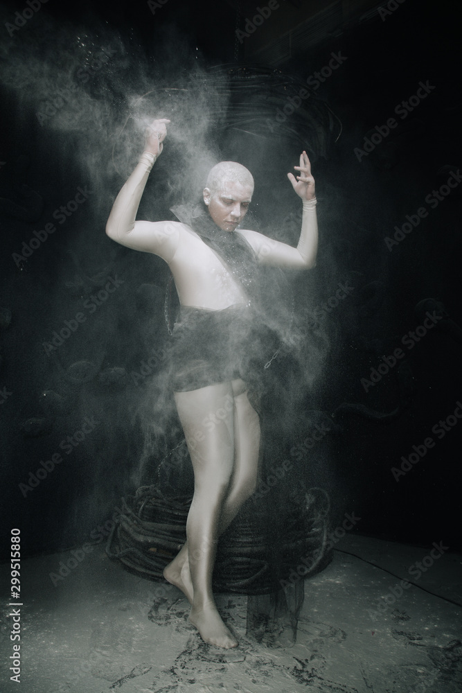 strange guy in tight beige leotard with dust on black studio background