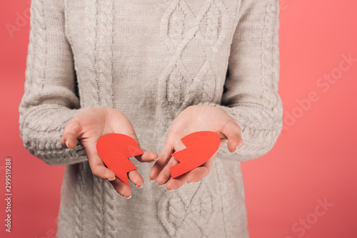 cropped view of woman holding paper artwork with broken heart on pink
