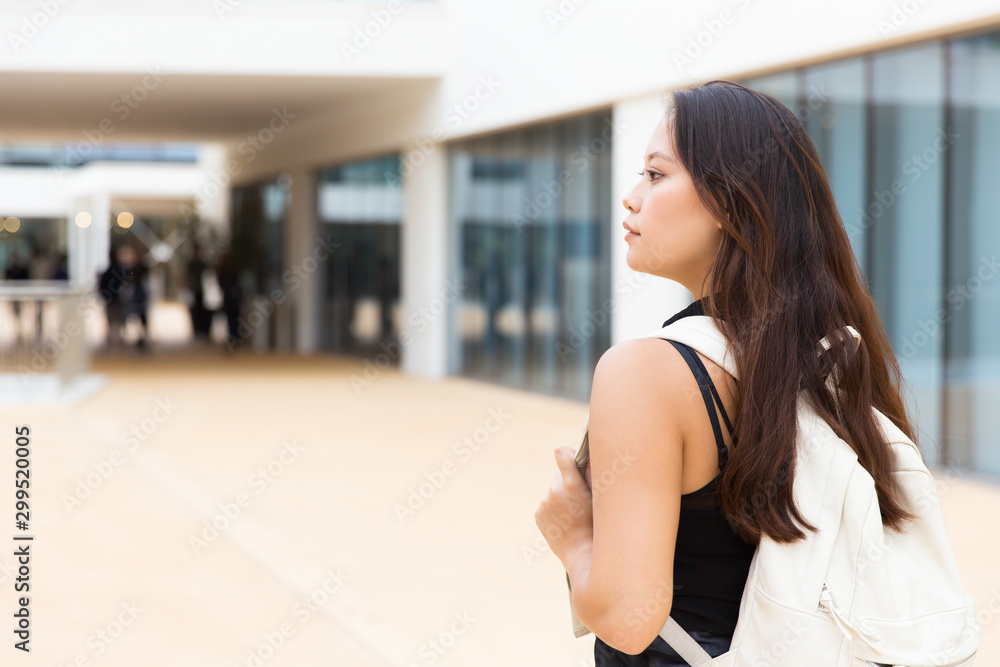 Pensive serious student girl on her way to college. Young Latin woman in casual with backpack walking outside, looking away. Girl with backpack concept