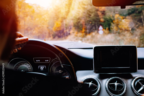 Portrait of caucasian driver holding hands on steering wheel and driving during sunset hour