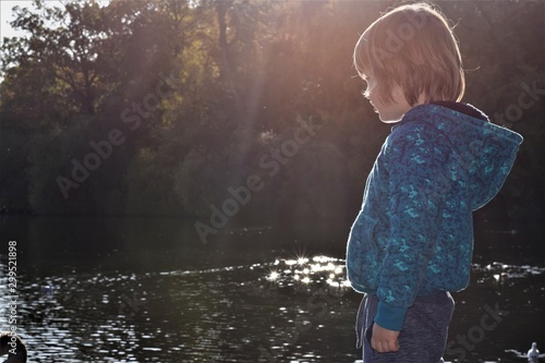 little boy standing by the lake and looking  at water