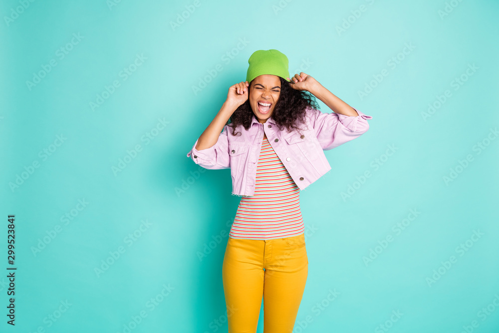 Photo of cheerful positive casual cute overjoyed rejoicing millennial wearing yellow pants pink jacket cap expressing emotions isolated pastel color teal background Photo of cheerful positive casual cute overjoyed rejoicing millennial wearing yellow pants pink jacket cap expressing emotions isolated pastel color teal background