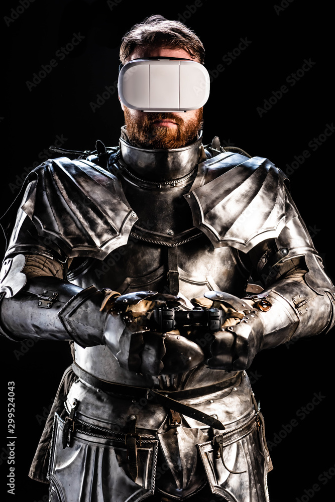 KYIV, UKRAINE - OCTOBER 9, 2019: knight with virtual reality headset in armor holding joystick on black background KYIV, UKRAINE - OCTOBER 9, 2019: knight with virtual reality headset in armor holding joystick on black background