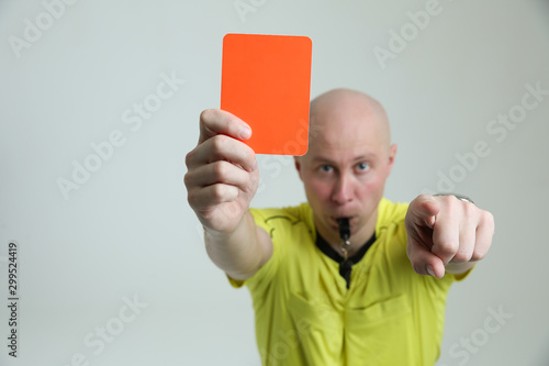 red card of a football referee close-up. hard gesture of a football referee. the referee shows a red card and looks into the frame. football referee shows a red card and points his finger at you