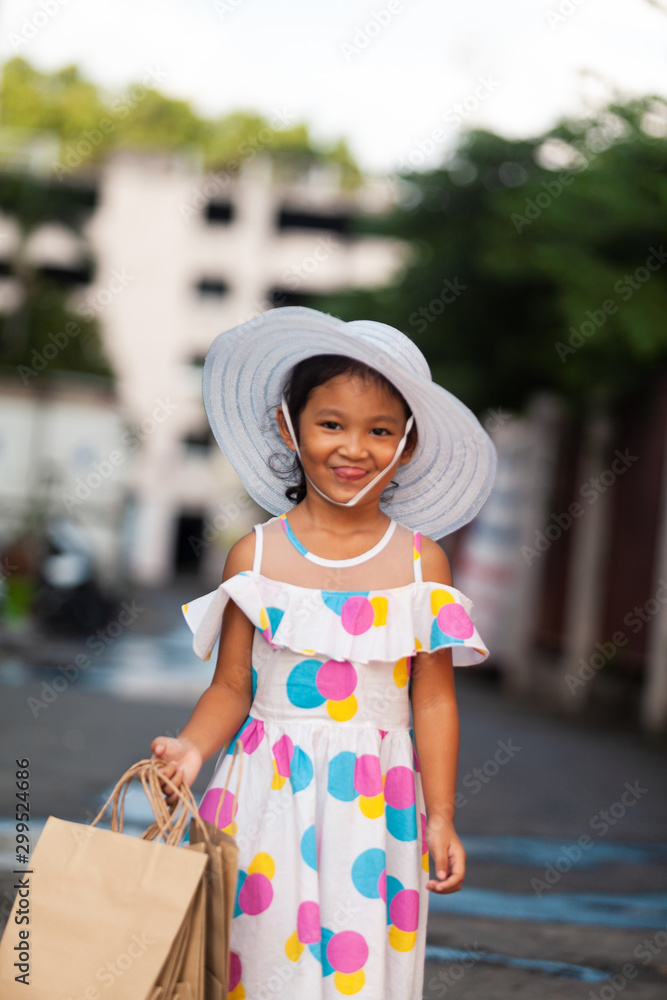 Portrait of beautiful smiling little girl wearing a dress with shopping bag outdoors