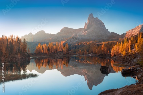 Autumn view of Lake Federa in Dolomites at sunset. Fantastic autumn scene with blue sky, majestic rocky mount and colorful trees glowing sunlight in Dolomites. Dolomite Alps with yellow larch trees