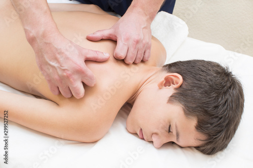 A teenage boy is given a medical massage of the back and neck.