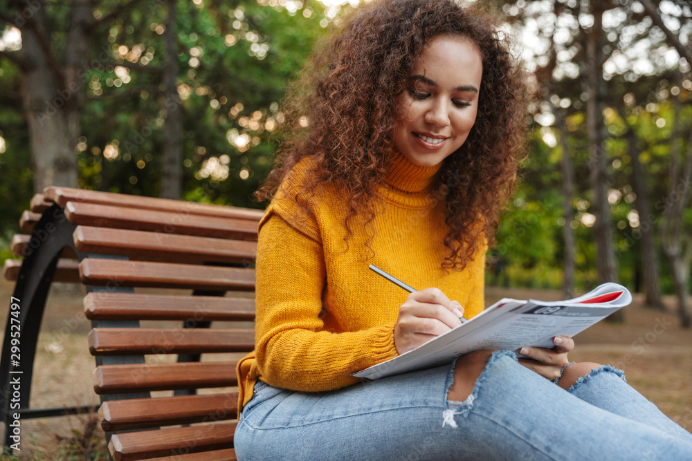 Obraz premium Woman sit on bench in park outdoors writing notes