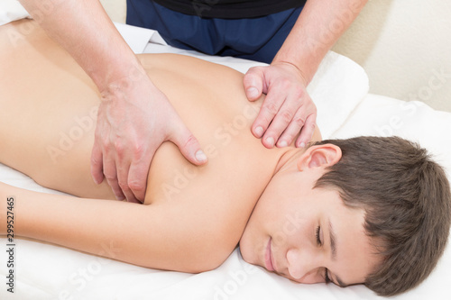 A teenage boy is given a medical massage of the back and neck.