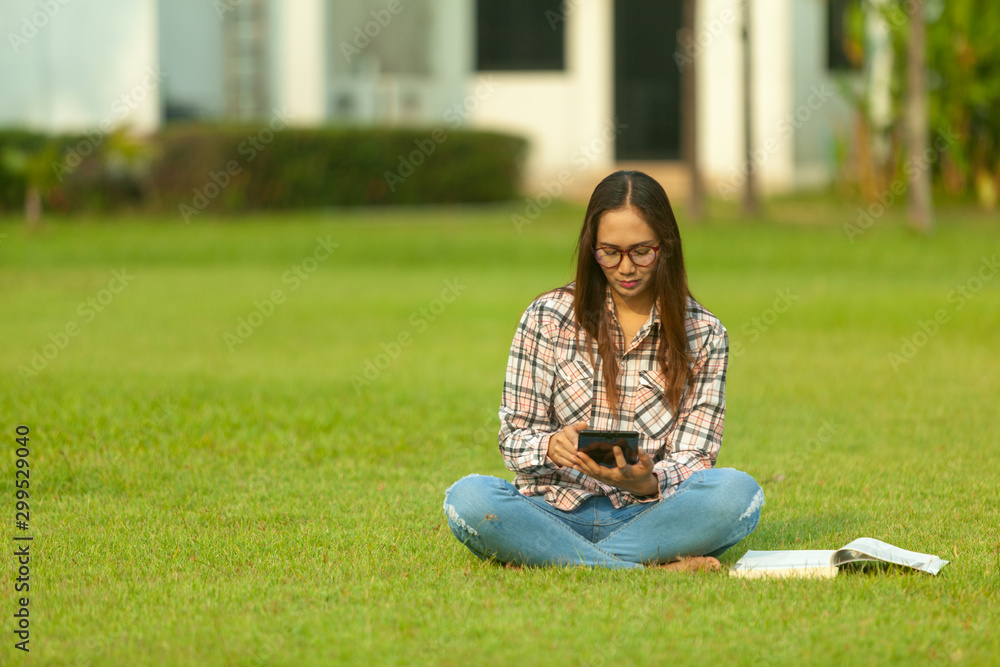 Women are relaxing in the park by reading books, listening to music, checking facebook mail read news mobile phones.