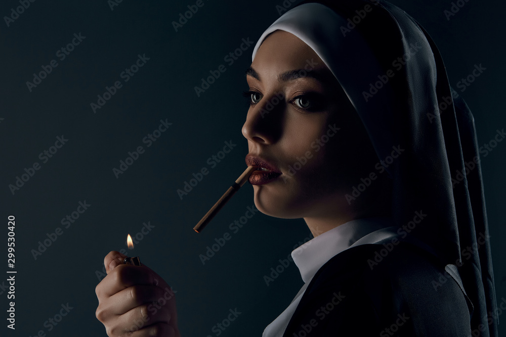 Half-turn portrait of a nun, taking on a black background. She wearing ...