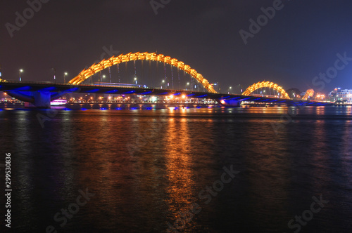 Yellow illuminated Dragon Bridge in Da Nang at night reflected in Han river, Vietnam  © Ilona