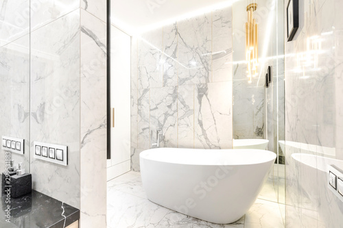 Luxury designer marble-tiled bathroom with gilded details for a cozy evening of body care and relax