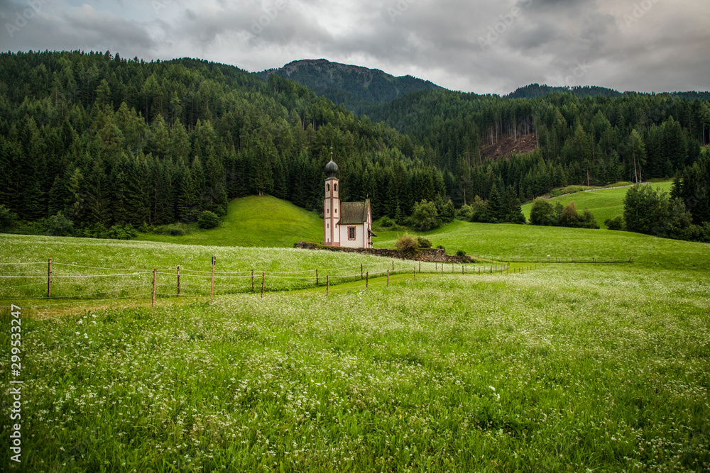 Dolomites, Italy - July, 2019: Green alpine valley with view of Santa Maddalena village church, Val di Funes, Dolomiti Mountains, Italy