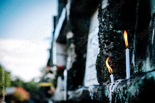 Burning or lighted candles in one of the apartment tombstones, during a visit in the cemetery on All Souls Day. Selective focus. Copy space.