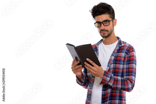Portrait of young bearded Persian hipster man reading book
