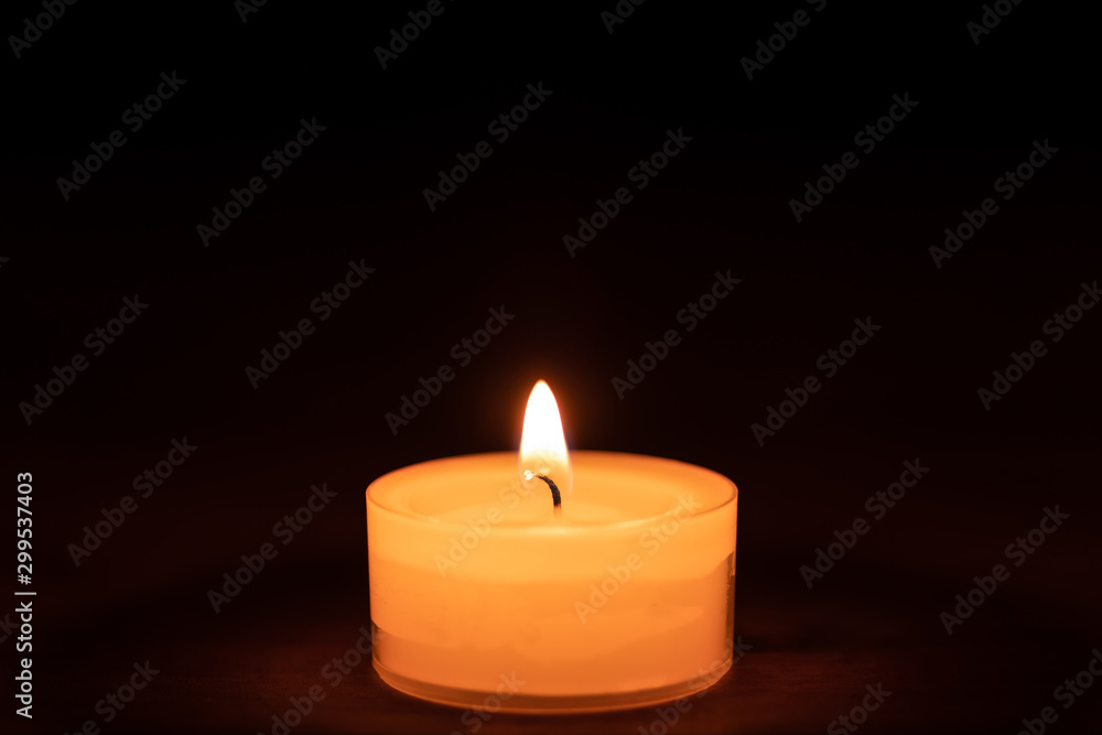Closeup of a candle on a wooden table with dark background - middle Closeup of a candle on a wooden table with dark background - middle