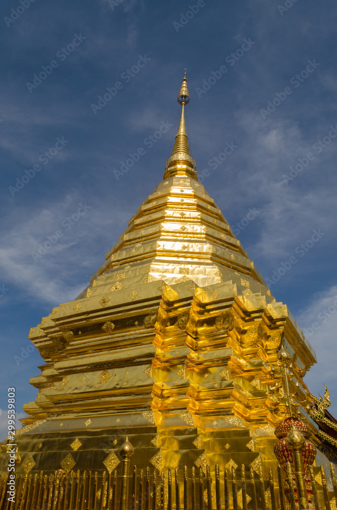 Fototapeta premium Glistening golden pagoda of a Buddhist temple against a clear blue sky