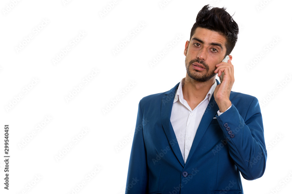 Young handsome bearded Persian businessman in suit using phone Young handsome bearded Persian businessman in suit using phone