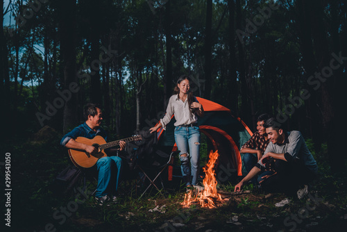 Group of friends are happy enjoying drunk and talking near a tent stay the night, they enjoy relaxing camp in the jungle vacation holidays concept.