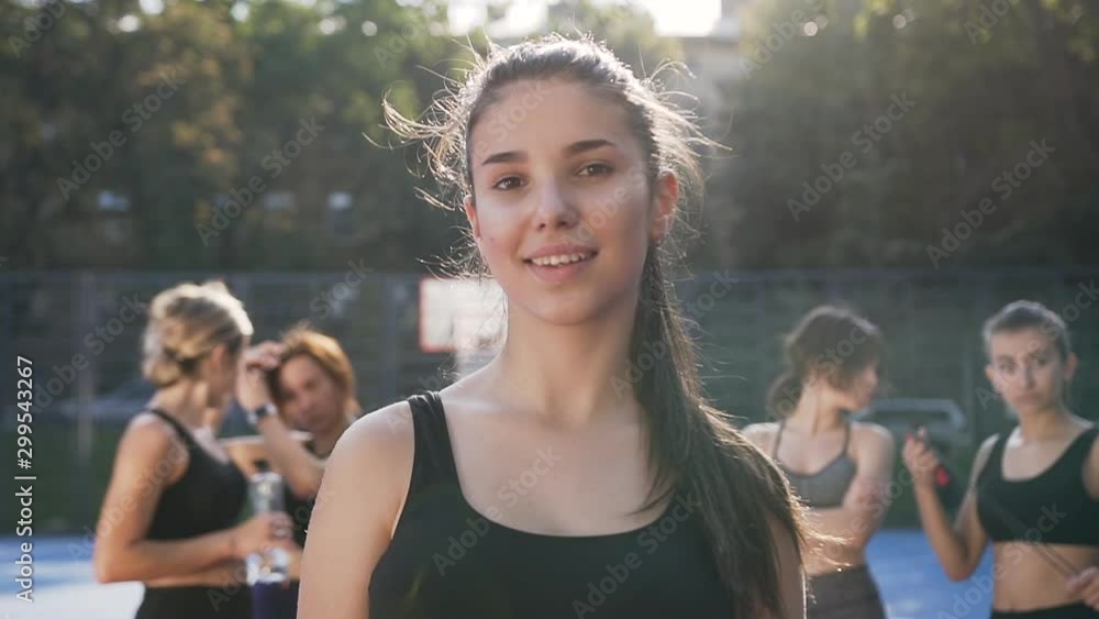 Beautiful portrait of pretty athletic 30-aged girl in sportswear looking at camera after fitness workout outdoors on the female fitness team background Beautiful portrait of pretty athletic 30-aged girl in sportswear looking at camera after fitness workout outdoors on the female fitness team background
