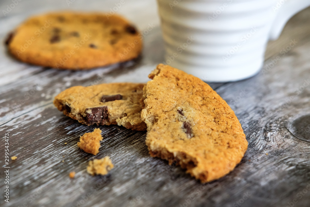 Freshly prepared chocolate chip cookies, partially eaten seen on a wooden kitchen surface together with a coffee mug. Freshly prepared chocolate chip cookies, partially eaten seen on a wooden kitchen surface together with a coffee mug.