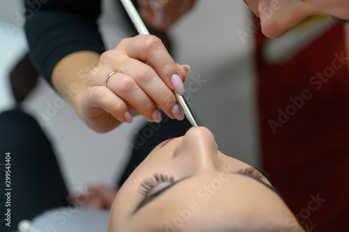 Studio photo of the work of a makeup artist by a hairdresser beautician. Creating beautiful makeup and hairstyles, rejuvenating the skin of the face. The professional is working with special tools.