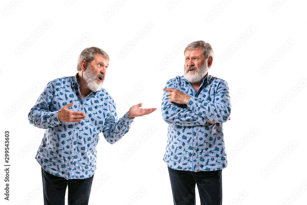 Senior man arguing with himself on white studio background. Concept of human emotions, expression, mental issues, internal conflict, split personality. Half-length portrait. Negative space. Pointing. Senior man arguing with himself on white studio background. Concept of human emotions, expression, mental issues, internal conflict, split personality. Half-length portrait. Negative space. Pointing.