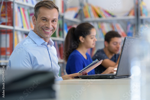 smily man studying with laptop computer on library desk