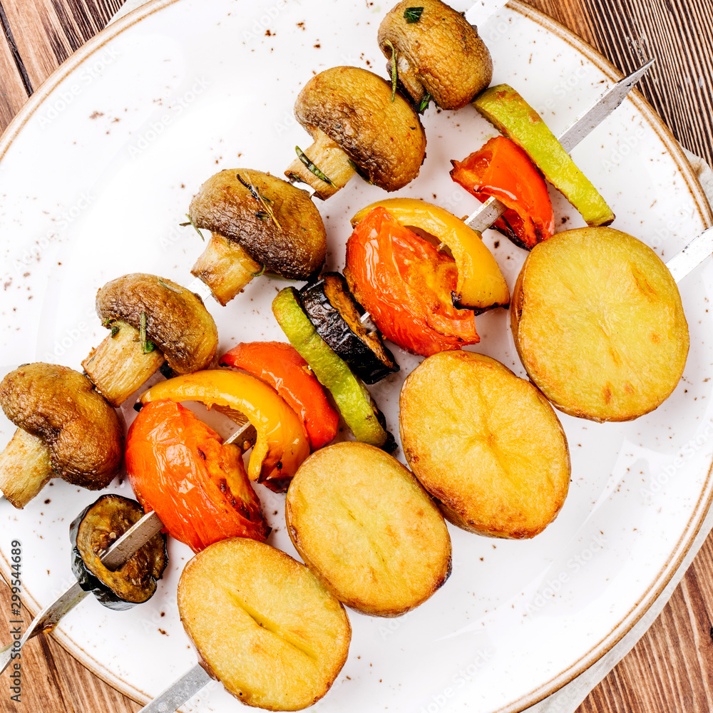 Variety of BBQ grilled vegetables lunch. skewers with  potatoes, tomatoes, mushrooms, eggplants, zucchinis  on  wood background.