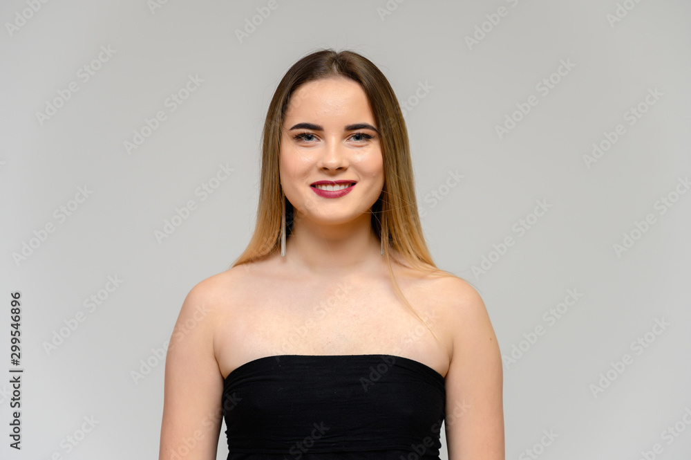 Studio portrait of a beautiful girl with long beautiful hair and excellent make-up on a gray background in different poses. She smiles. Studio portrait of a beautiful girl with long beautiful hair and excellent make-up on a gray background in different poses. She smiles.