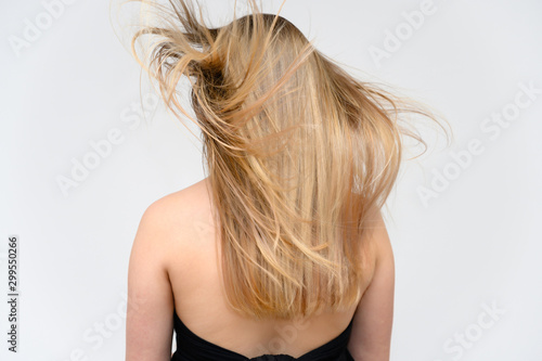 Studio large photo portrait of a beautiful girl with long beautiful fluttering hair on a white background. Back view.